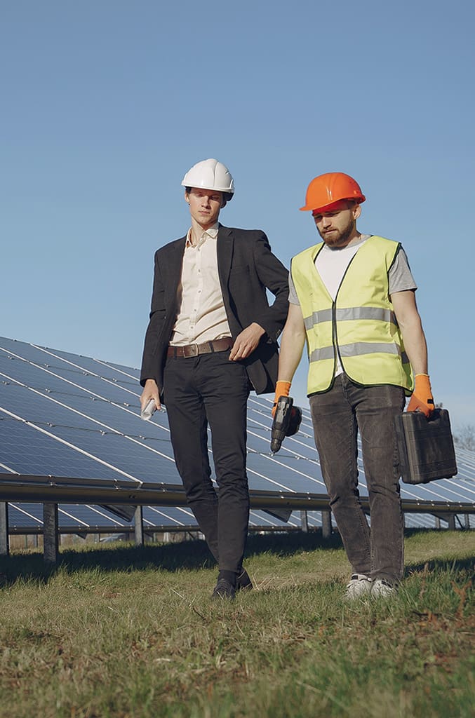 an engineer and contractor walking next to each other alongside a row of solar panels
