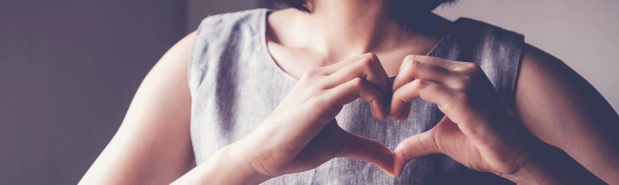 A close up of someone doing a heart symbol with their hands