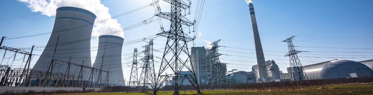 A picture of a nuclear powerplant surrounded by electricity pylons and substations