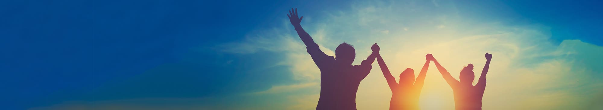 A picture of 3 people in silhouette all holding hands in the air, blue sky and clouds in the background