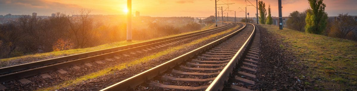 a picture of a railway track with a sunset background