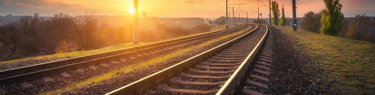 a picture of a railway track with a sunset background
