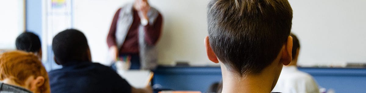 I picture of the back of a young boys head in a classroom environment