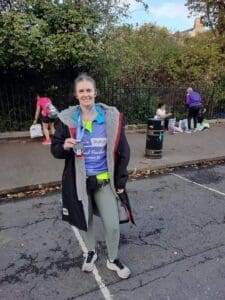Maria from the Glasshouse Support Team holding her medal after finishing a marathon.