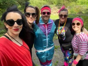 The Marketing Team stood wearing 80's fancy dress whilst doing their charity work for PSPA
