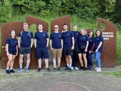 The Woking Team stood smiling at the camera about to do their charity walk on the North Downs Way