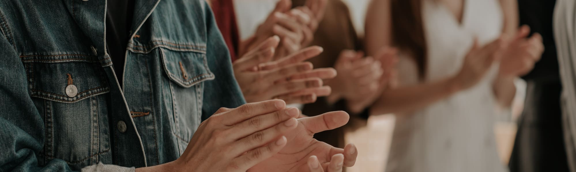 A close up of people stood clapping their hands