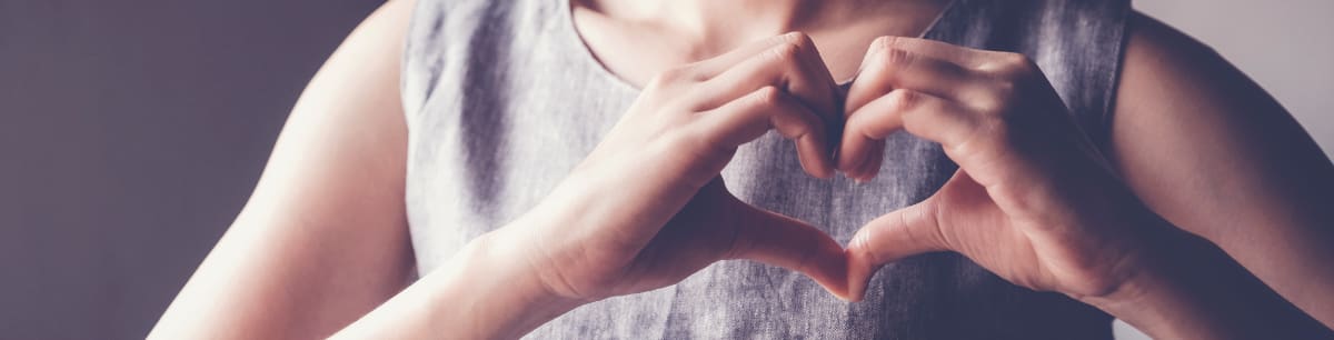 A woman making a heart shape with her hands in front of her shest