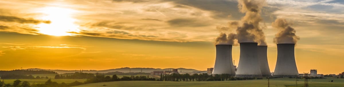 Three nuclear cooling towers in the distance against a sunset background.