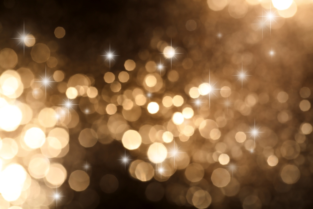 Blurred golden lights with glowing bokeh and small sparkling highlights.