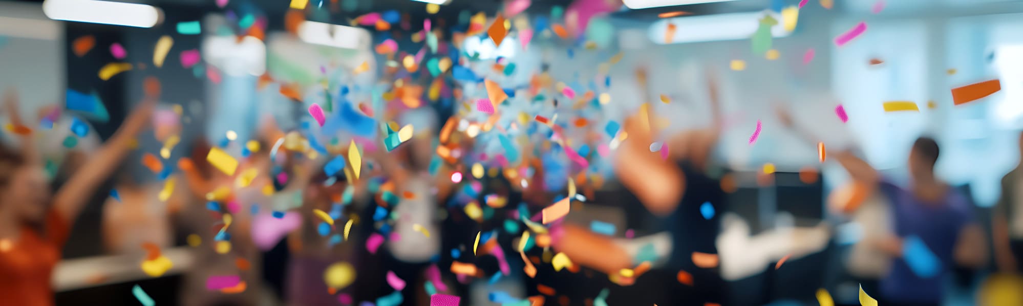 Colourful confetti falling in a room with a blurred background, creating a festive atmosphere.