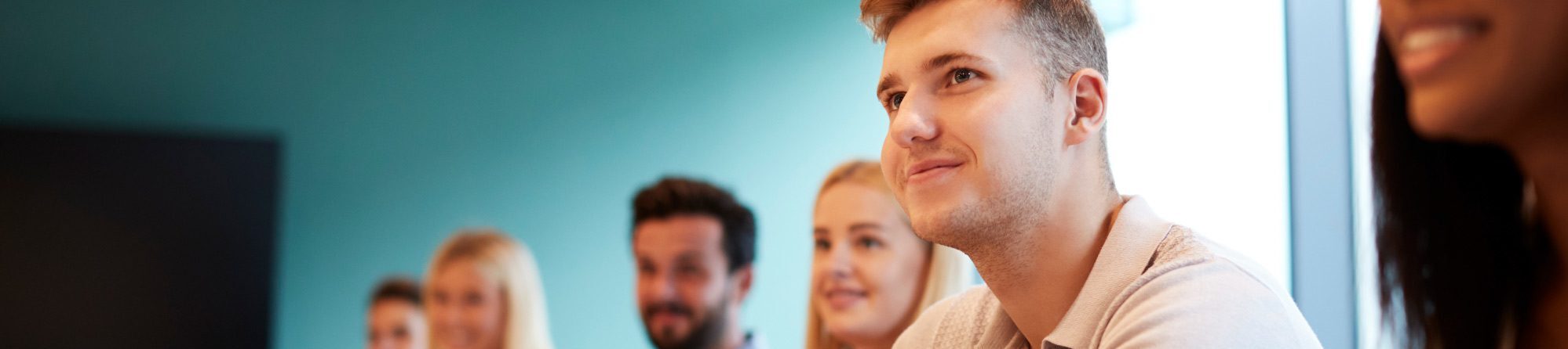 People sit at a conference table taking notes during a meeting in a modern office room.