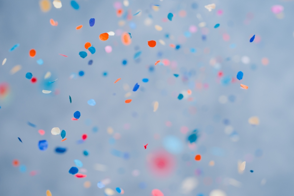 Coloured paper confetti scattered and falling against a soft blurred background.