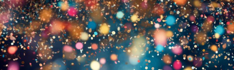 Blurred colourful lights and scattered confetti creating a soft glowing abstract background.