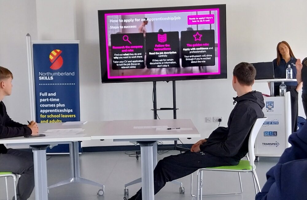 Person presents apprenticeship information on a screen to seated students in a classroom.