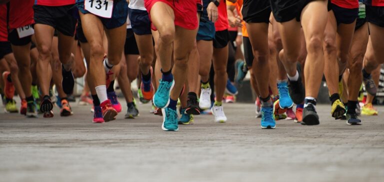 Close-up of runners’ legs and trainers moving together during a road race event.