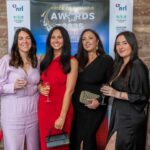 Four people pose with drinks in front of a Pride of Cumbria Awards 2026 backdrop.