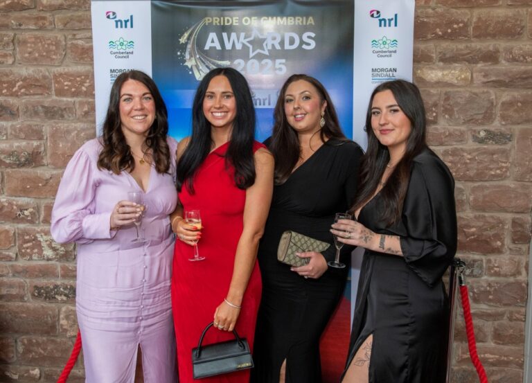 Four people pose with drinks in front of a Pride of Cumbria Awards 2026 backdrop.